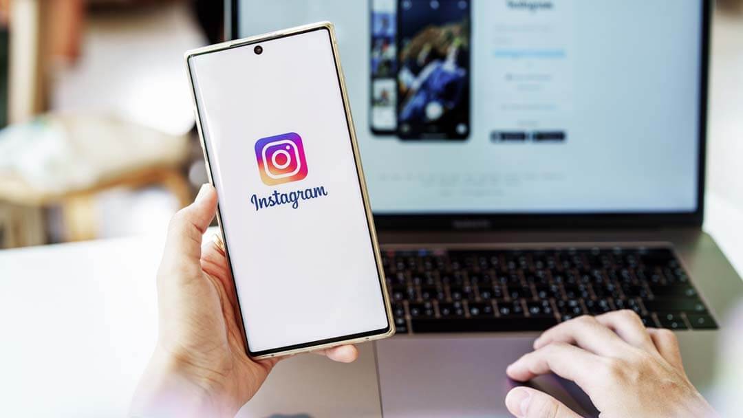 Smartphone with Instagram logo and laptop in the background, showing expert ad management by an advertising agency near you.